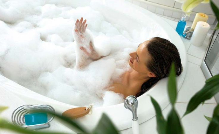 a biohacking lady enjoys bath in bath tub to free herself from negative energies at home