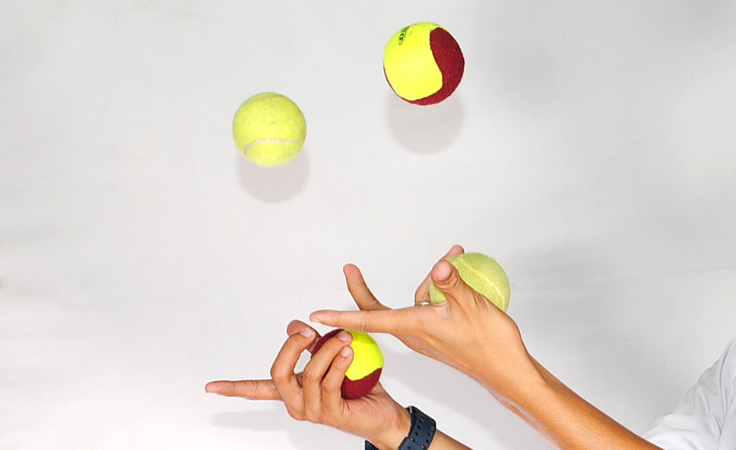 a biohacker juggles four balls as a brain balancing exercise
