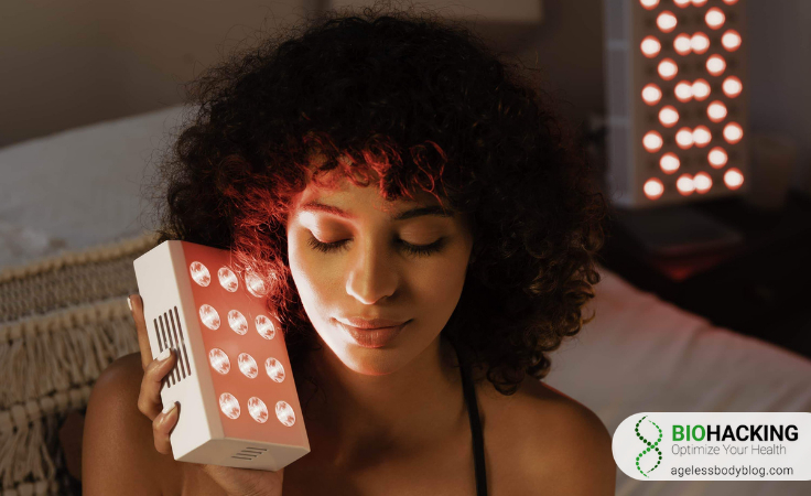 a curly-haired biohacker holds joovv red light therapy box close to their hair
